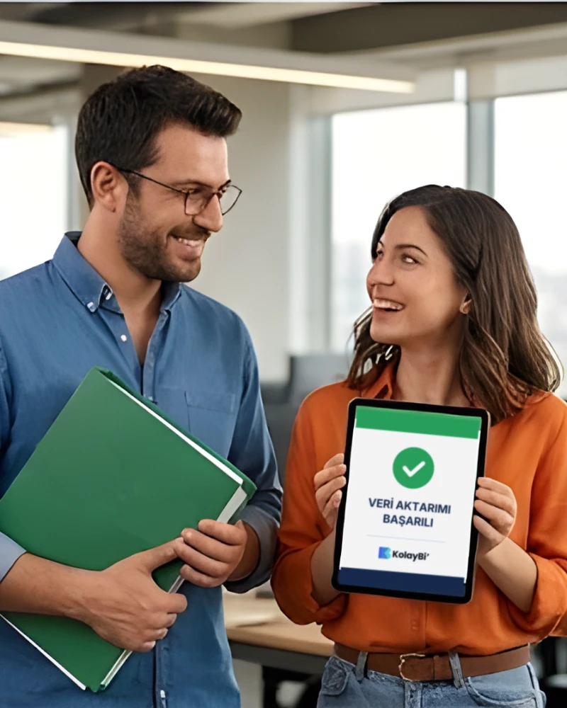 Tablette “Veri aktarımı başarılı” ekranını gösteren iki iş arkadaşı